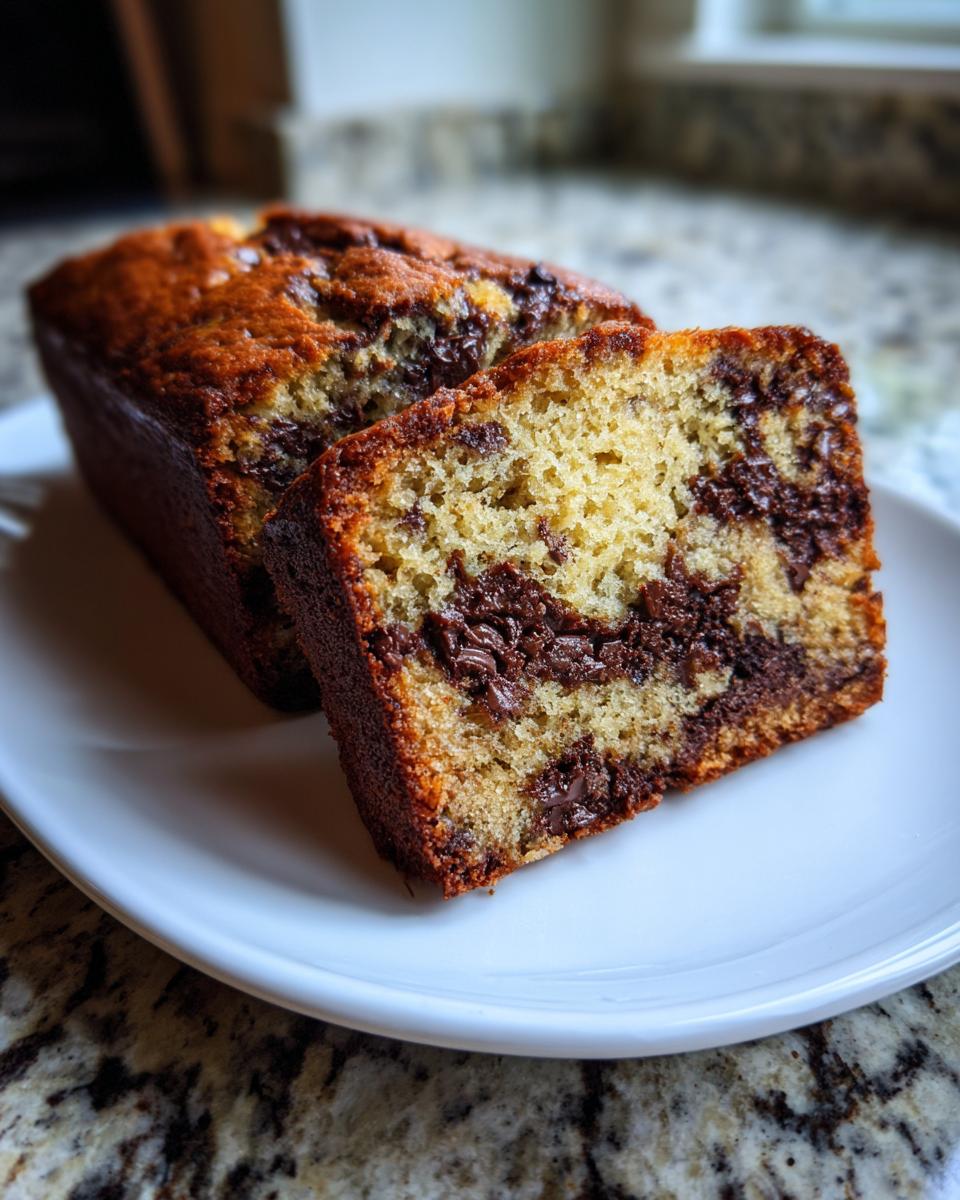 Close-up of a slice of moist peanut butter chocolate chip banana bread with visible chocolate swirls.