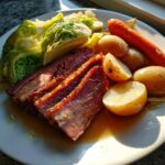 Plated serving of sliced slow cooker corned beef and cabbage with potatoes and carrots.