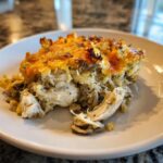 A close-up serving of creamy rotisserie chicken wild rice casserole with a golden, cheesy crust.