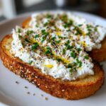 Close-up of savory cottage cheese toast topped with everything bagel seasoning, fresh chives, and a drizzle of olive oil.