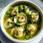 Close-up of savory thai coconut curry dumpling soup filled with dumplings and topped with fresh cilantro.