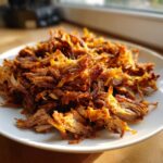 Close-up of crispy, shredded, seasoned meat, perfect for homemade doner kebab, served on a white plate.