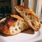 Close-up of a freshly baked sourdough yeast bread, cut open to show the airy, open crumb structure.