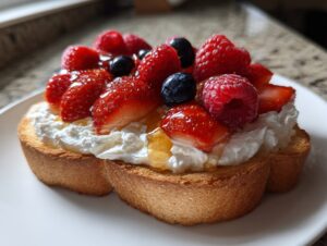 Close-up of whipped cottage cheese toast topped with fresh strawberries, raspberries, blueberries, and drizzled with honey.