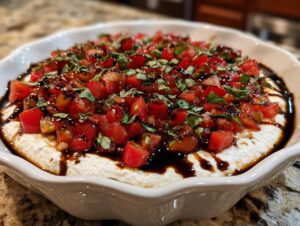 Close-up of the finished boursin bruschetta dip recipe topped with diced tomatoes, basil, and balsamic glaze.