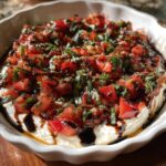 Close-up of a creamy boursin bruschetta dip recipe topped with diced tomatoes, fresh basil, and a balsamic glaze.