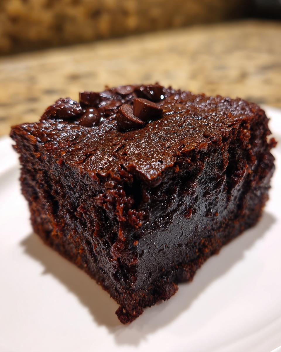 Close-up of a rich, fudgy slice of black bean brownie batter dessert topped with chocolate chips.