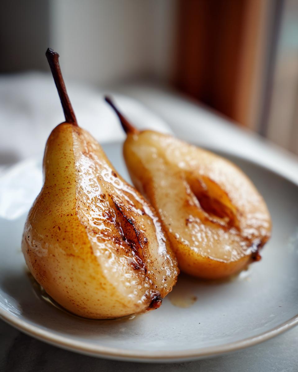 Two halves of glistening, caramelized baked pears recipe resting on a light blue plate.