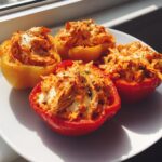 Four halves of bell peppers stuffed with shredded buffalo chicken and melted cheese, ready to eat. These are high protein buffalo chicken stuffed peppers.