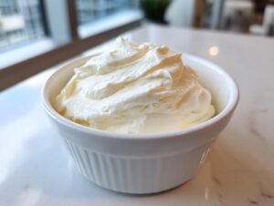 A close-up of thick, creamy homemade mayonnaise perfectly whipped in a small white ramekin.