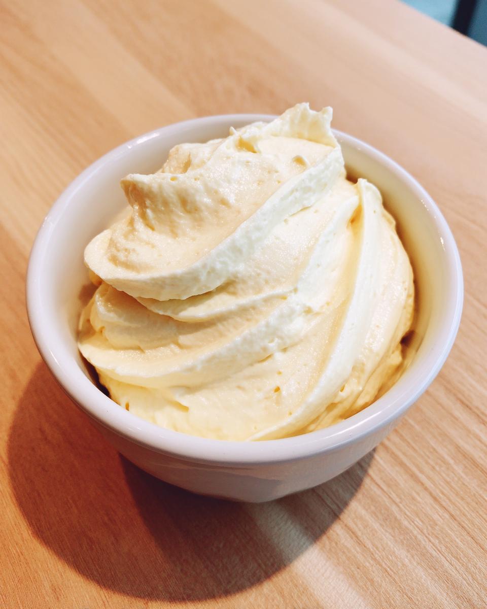 A small white bowl filled with freshly made, pale yellow homemade mayonnaise recipe avocado oil, piped decoratively.