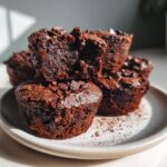 A stack of rich, dark black bean brownie bites topped with chocolate chips, one cut open to show the fudgy interior.