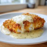 A golden, crispy piece of parmesan crusted chicken generously topped with creamy garlic sauce.