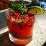 Close-up of a frosty strawberry basil margarita recipe cocktail garnished with fresh basil and a lime wedge.