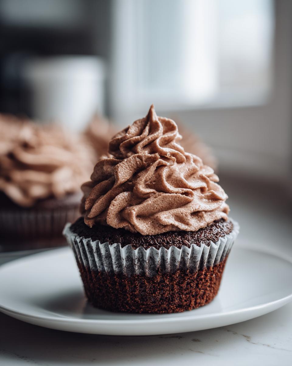 Close-up of a dark chocolate cupcake topped with perfectly piped whipped chocolate ganache.