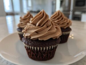 Three decadent chocolate cupcakes topped with perfectly piped whipped chocolate ganache frosting.
