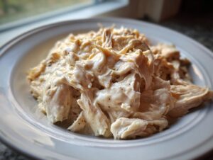 Close-up of shredded chicken coated in a creamy sauce, representing the Crockpot Olive Garden Chicken recipe.