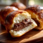 A close-up of an italian chocolate maritozzi bread roll sliced open, revealing a rich chocolate hazelnut filling.